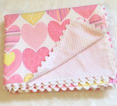 a pink and yellow heart print blanket on a white tablecloth with ruffles