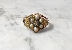 a gold ring with pearls on it sitting on a marble surface