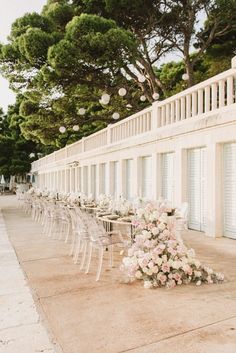 the tables are lined up with chairs and flowers on them for an outdoor wedding reception