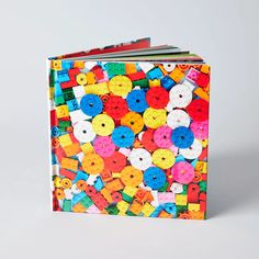 an open book with colorful buttons on the front and back cover, sitting on a white surface