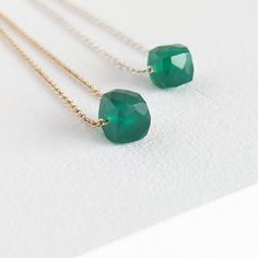 The Emerald Green Onyx Cube Necklace is a stunning piece of jewellery that showcases a faceted emerald green cube on a delicate cable chain. This minimalist design is available in both sterling silver and gold-filled metals, allowing you to choose the perfect option to suit your style. You can also select between a 6mm or an 8mm stone size for a personalized touch. Wearing Green Onyx is believed to attract positive energy and boost confidence. It is also commonly used as a substitute for emerald Green Briolette Emerald Necklace, Green Briolette Necklace In Fine Jewelry Style, Green Briolette Necklace Fine Jewelry, Green Faceted Necklace Fine Jewelry, Modern Faceted Necklace As A Gift, Green Faceted Fine Jewelry Necklace, Modern Jewelry For May Birthstone Gift, Emerald Briolette Gemstone Necklace, Elegant Green Jewelry With Box Chain