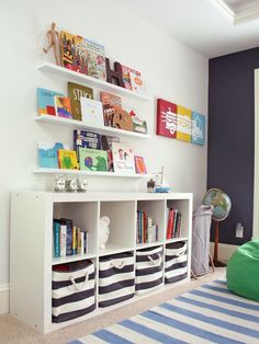 a white book shelf filled with books next to a green bean bag