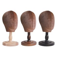 three wigs on wooden stand with one standing up and the other sitting back to back