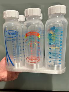 three plastic bottles with different types of drinks in them are held by someone's hand