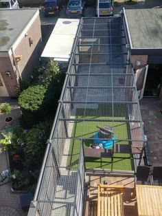 an aerial view of a backyard with a bird cage on the roof and grass in the yard