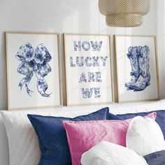 three framed pictures hang on the wall above a bed with blue and pink pillows,