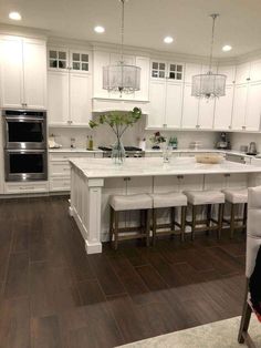 a large kitchen with white cabinets and wooden floors