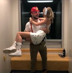 a man holding a woman in his arms while they both wear white shoes and red caps