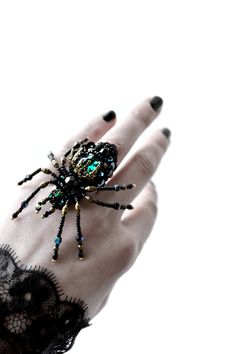 a woman's hand with a spider ring on top of her finger and black lace