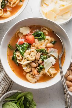 two bowls filled with pasta and spinach soup