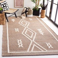 a room with a chair, rug and plants in the corner on the floor next to a window