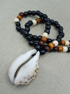 The large Cowrie shell necklace is approximately 26 inches long. the shell is approximately 3 inches long and 2 inches wide. It is beaded with black, brown and off white beads. If you have any questions please feel free to contact us at anytime. All shipping options are available. All items will be shipped out Monday through Friday. Receipts will be emailed out for immediate access. All items will be shipped out carefully and every shipment can be made with extra insurance upon request. All othe Black Necklaces With Large Beads For Beach, Black Beaded Necklace For Vacation, Black Wooden Beads Necklace For Beach, Brown Necklaces With Black Beads For Beach, Brown Beaded Shell Necklace, Black Wooden Beads For Beach, Beaded Brown Shell Necklace For Beach, Brown Beaded Shell Necklace For The Beach, Brown Shell Necklace For Vacation