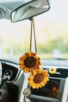 the sunflowers are hanging from the car's rearview mirror holder as if they were crocheted