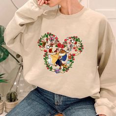 a woman sitting on a chair wearing a sweatshirt with an image of beauty and the beast