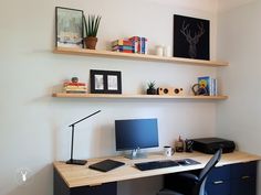 a desk with a keyboard, mouse and monitor on it next to a wall mounted bookshelf