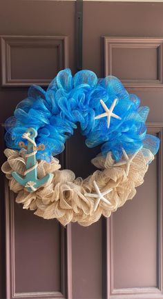 a blue wreath with an anchor, starfish and net hanging from the front door