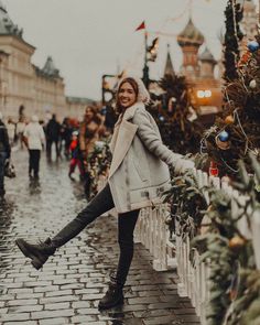 a woman standing in front of a christmas tree with her legs spread out and smiling