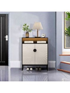 a white and black cabinet sitting in front of a door with a lamp on top