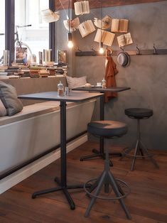 two stools sit in front of a table with books hanging from the ceiling above it