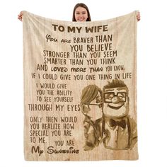 a woman holding up a wooden blanket with an image of two people and the words to my wife