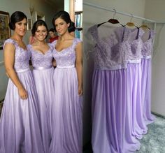 three bridesmaids pose in front of dresses hanging on a rack and one is wearing a purple dress