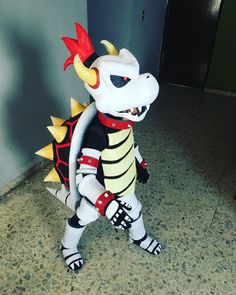 a white and black stuffed animal standing in front of a door with spikes on it's head