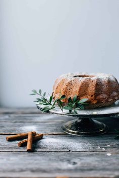 a bundt cake sitting on top of a wooden table next to two cinnamon sticks