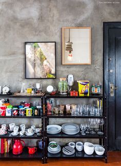 a shelf filled with dishes and cups next to a painting on the wall above it