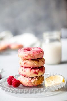 a stack of raspberry donuts sitting on top of a plate next to a glass of milk