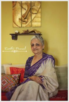 a woman sitting on top of a couch next to a wall with paintings above her