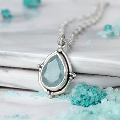 A glistening teardrop of aquamarine gemstones suspends from a delicate chain in this stunning necklace. The vibrant blue-green hue adds a pop of color to any outfit, making it a versatile accessory for any occasion. The simple yet sophisticated design is sure to become a go-to piece in your jewelry collection. This necklace features a natural, genuine, unique gemstone handpicked from our current collection. The actual gemstone you receive will be one-of-a-kind and may be different from the photo Cheap Sterling Silver Gemstone Jewelry, Affordable Sterling Silver Crystal Necklaces For Gifts, Affordable Large Pendant Sterling Silver Necklace, Cheap Silver Crystal Necklaces With Natural Stones, Affordable Sterling Silver Crystal Necklace Gift, Palm Necklace, Silver Necklace For Women, Sterling Silver Heart Pendant, Aquamarine Pendant