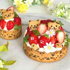 two cakes decorated with strawberries and teddy bears are on a table next to flowers