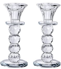 two clear glass candlesticks sitting side by side on top of each other in front of a white background