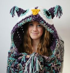 a young woman wearing a crocheted owl hat and scarf with tassels