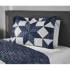 a blue and white quilted pillow on a bed