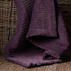 a purple blanket sitting on top of a wicker chair