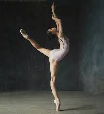 a woman in white leotard standing on one leg with her arms up and legs spread out