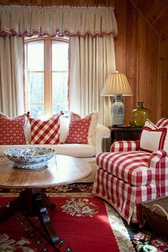 a living room with red and white checkered couches, coffee table and lamp