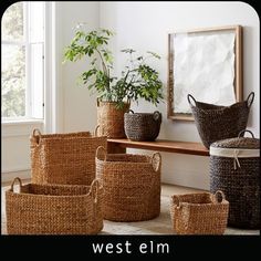 several woven baskets sit in front of a window on a rug next to a potted plant