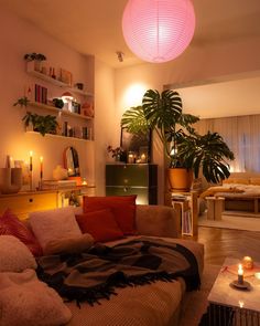 a living room filled with furniture and a pink light hanging over the top of it