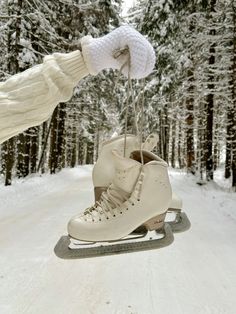 a pair of ice skates being held by someone's hand in the snow