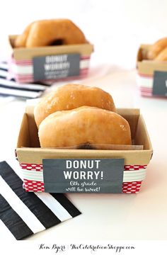 donuts are in a box on a table with black and white striped napkins