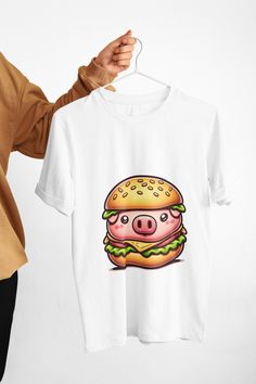 Embrace your fun side with our Pig Burger T-Shirt, the ultimate conversation piece for anyone with a taste for whimsy in their wardrobe. Ideal for foodies and novelty fashion lovers alike, this graphic tee is as comfortable as it is eye-catching. Showcasing a playful pig burger design, it's a quirky addition to your casual wear or a unique gift for that person who delights in the unexpected. We utilize the authentic Bella Canvas 3001 brand, renowned for its UNISEX design, making it one of the mo Novelty Cotton Tops With Sublimation Print, Novelty Cotton Top With Sublimation Print, Novelty Cartoon Print Crew Neck T-shirt, Novelty White T-shirt For Streetwear, White Novelty T-shirt For Streetwear, Novelty Cotton Tops With Cartoon Print, Novelty Clothing, Statement Shirt, Conversation Piece