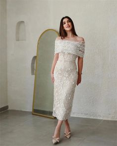 a woman standing in front of a mirror wearing a dress with off the shoulder sleeves