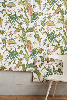 a white chair sitting in front of a wall with a flowered pattern on it