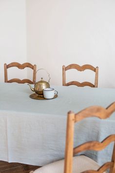 there is a teapot on the table with two chairs next to it and a cup