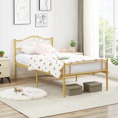 a bedroom with white walls and wooden flooring has a gold metal bed frame in the middle