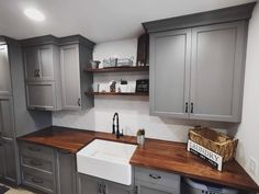 a kitchen with gray cabinets and wooden counter tops in the center is a white dishwasher