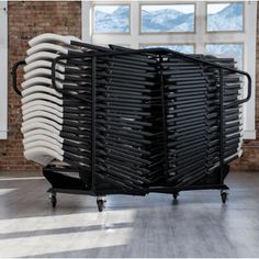 a stack of chairs sitting on top of a black cart in front of a window