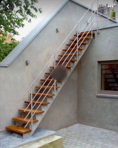 a set of stairs leading up to a window on the side of a building with brick flooring